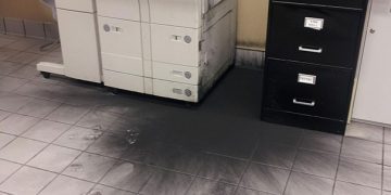 Office printer with exploded toner creating a messy black spill.