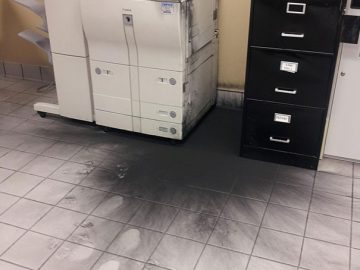 Office printer with exploded toner creating a messy black spill.