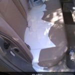 Car backseat with white paint spill and overturned paint can.