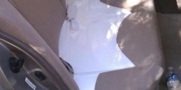 Car backseat with white paint spill and overturned paint can.