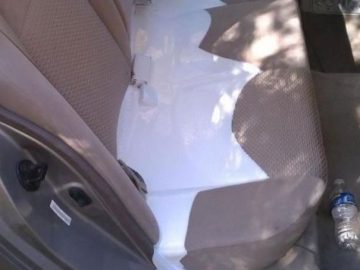 Car backseat with white paint spill and overturned paint can.