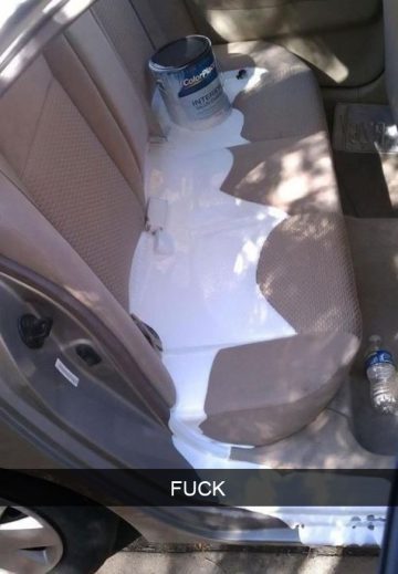 Car backseat with white paint spill and overturned paint can.