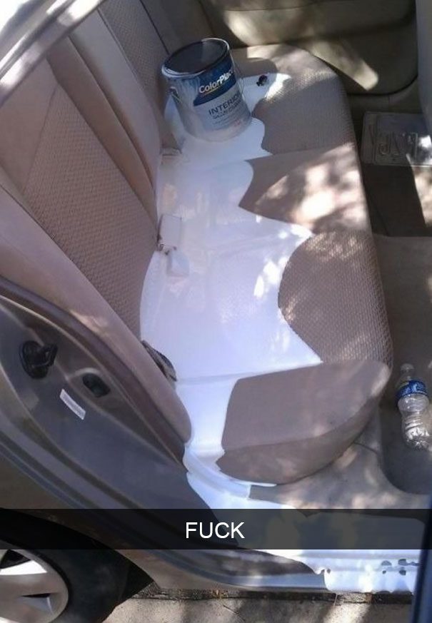 Car backseat with white paint spill and overturned paint can.