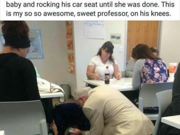 Professor kneeling to feed a baby in a classroom setting.