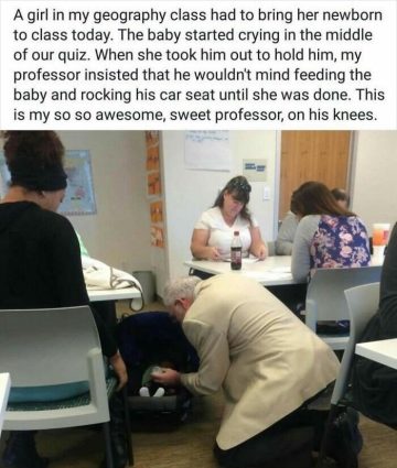 Professor kneeling to feed a baby in a classroom setting.