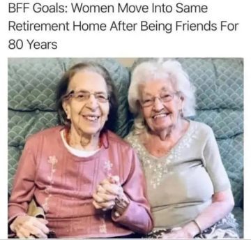 Two elderly women smiling, holding hands in a retirement home.