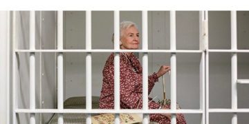 Elderly woman in jail cell, looking for alternative retirement plan.