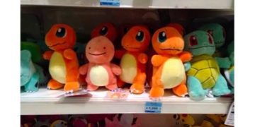 Plush Charmander looking anxious next to friends on a shelf.