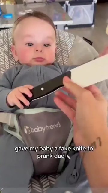 Baby holding a fake knife for a prank on dad
