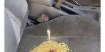 Spaghetti spilled on car seat with a fork sticking out