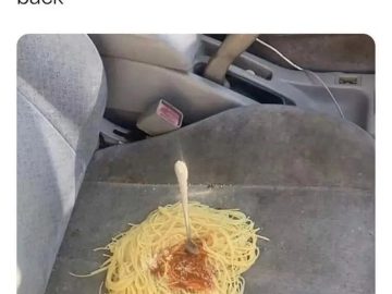 Spaghetti spilled on car seat with a fork sticking out