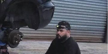 Man sitting in front of car, pondering DIY project gone long