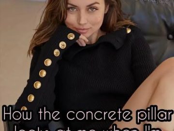 Woman in black sweater with text about concrete pillar staring.