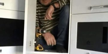 Contractor inside a cabinet proving its sturdiness with a smile.