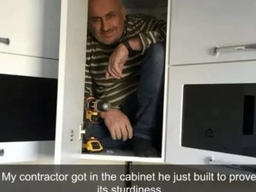 Contractor inside a cabinet proving its sturdiness with a smile.