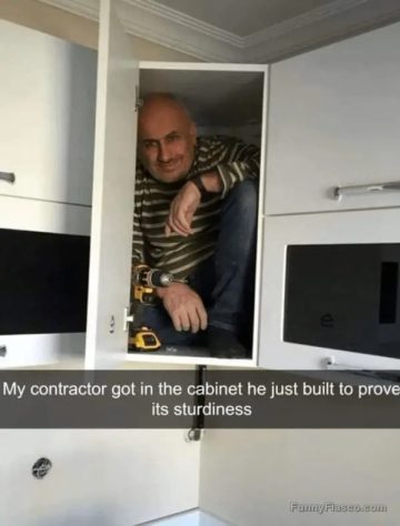 Contractor inside a cabinet proving its sturdiness with a smile.