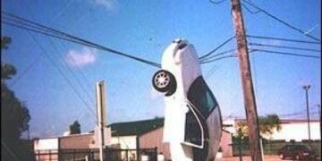 Car hanging on wires with "Hey You Can't Park There" text overlay.