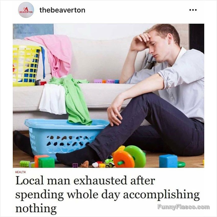 Exhausted man surrounded by laundry and toys after a lazy day.