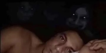 Man in bed wide awake facing wall with creepy shadows.