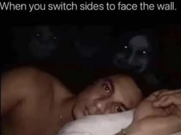 Man in bed wide awake facing wall with creepy shadows.
