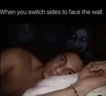 Man in bed wide awake facing wall with creepy shadows.
