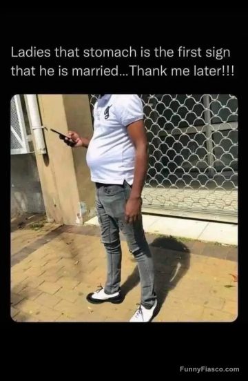 Man with a visible belly standing outside texting on his phone.