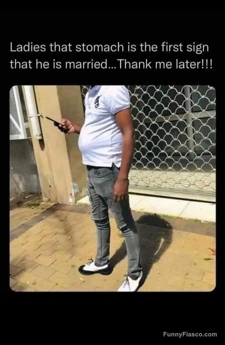 Man with a visible belly standing outside texting on his phone.