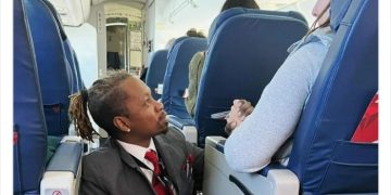 Flight attendant kneeling and comforting a nervous passenger.