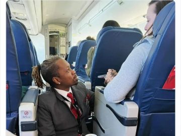 Flight attendant kneeling and comforting a nervous passenger.