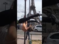 A woman hanging upside down from a street pole near the Eiffel Tower before slipping into an awkward fail.