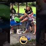 Outdoor party scene with a woman at a picnic table reacting as a green object flies toward her during a fail compilation.