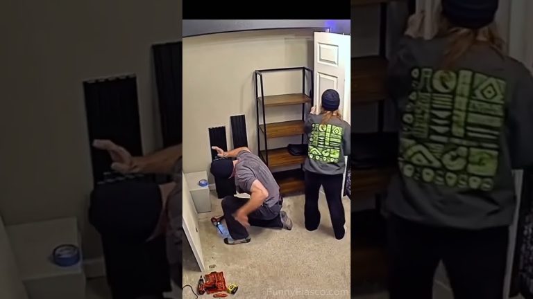 A woman carrying a long white board accidentally bumps into a kneeling man during a DIY shelf project.